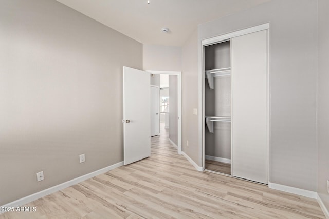 unfurnished bedroom with light wood-style floors, baseboards, and a closet