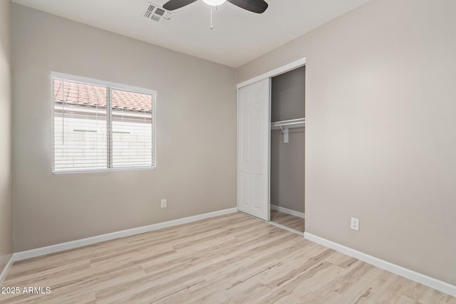 unfurnished bedroom featuring baseboards, visible vents, a ceiling fan, light wood-style floors, and a closet