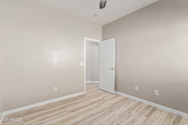 spare room with light wood finished floors, a ceiling fan, and baseboards