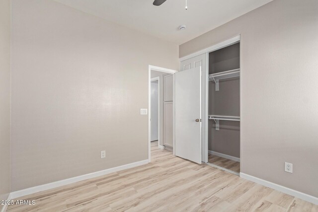 unfurnished bedroom featuring light wood finished floors, a closet, a ceiling fan, and baseboards