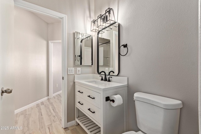 bathroom with toilet, baseboards, wood finished floors, and vanity