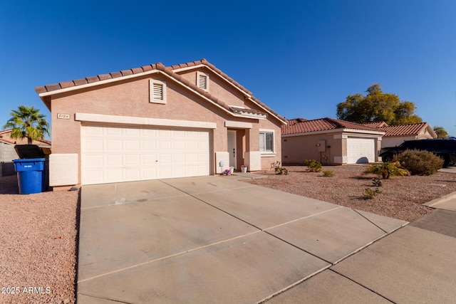 view of front of home with a garage, a tiled roof, concrete driveway, and stucco siding