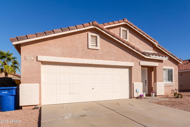 view of front of home featuring a garage, driveway, a tiled roof, and stucco siding