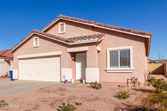 mediterranean / spanish-style home with an attached garage, a tiled roof, concrete driveway, and stucco siding