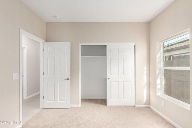 unfurnished bedroom with a closet, light colored carpet, and multiple windows