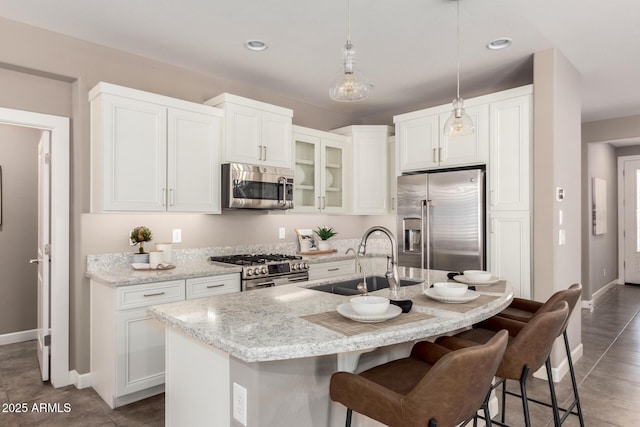 36145 N Desert Tea Dr, Queen Creek, AZ 85140 - kitchen featuring stainless steel appliances, a sink, a kitchen bar, baseboards, and white cabinetry