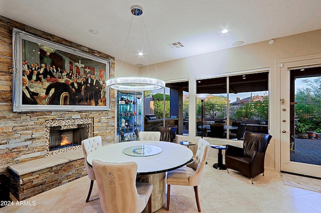 tiled dining space with an inviting chandelier and a stone fireplace