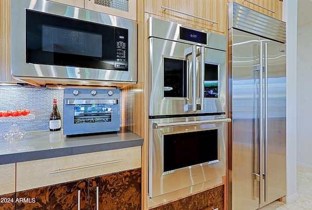 kitchen with backsplash, built in appliances, and light brown cabinets