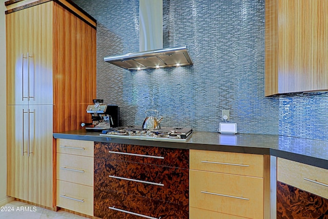 kitchen featuring light tile patterned floors, wall chimney range hood, light brown cabinetry, and stainless steel gas cooktop