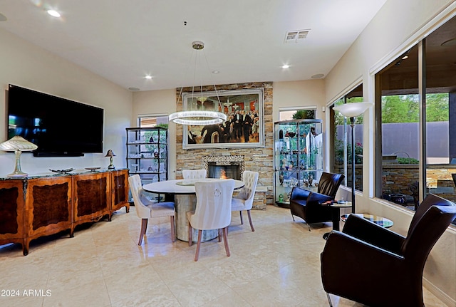 dining space featuring an inviting chandelier, a stone fireplace, and a healthy amount of sunlight