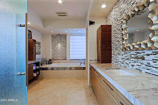 bathroom with tiled tub, decorative backsplash, and vanity