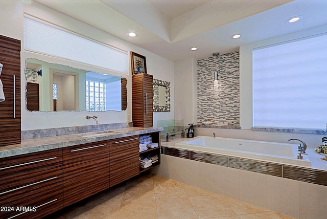 bathroom with tile patterned flooring, vanity, and tiled bath