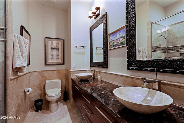 bathroom featuring tile patterned floors, walk in shower, vanity, tile walls, and toilet