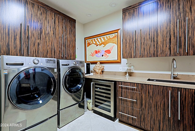 laundry room featuring cabinets, sink, light tile patterned floors, beverage cooler, and washing machine and clothes dryer