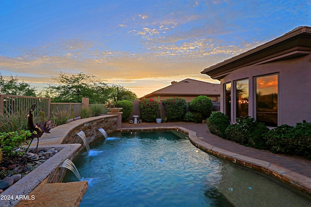 pool at dusk featuring pool water feature