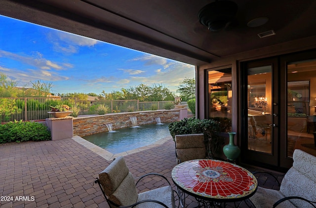 patio terrace at dusk with a fenced in pool and pool water feature