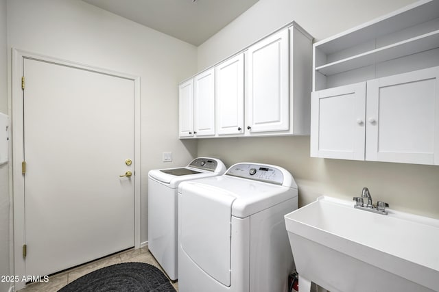 washroom with a sink, cabinet space, and washer and clothes dryer