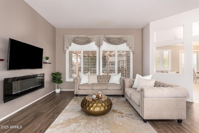 living area with baseboards, a glass covered fireplace, and wood tiled floor