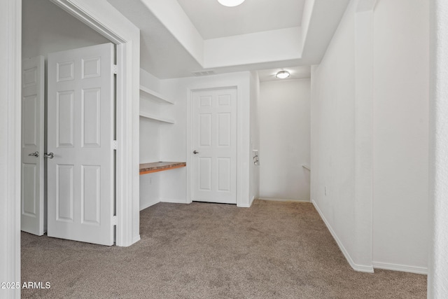 interior space featuring a raised ceiling, carpet, visible vents, and baseboards