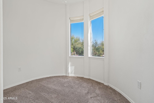 carpeted empty room featuring baseboards