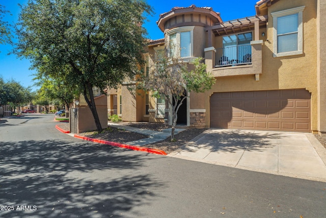 view of front of property with stucco siding, concrete driveway, an attached garage, and a tile roof