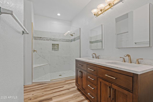 full bathroom featuring double vanity, wood finished floors, walk in shower, and a sink