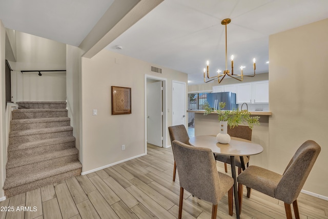 5808 E Brown Rd Unit 49, Mesa, AZ 85205 - dining area with a chandelier, light wood-style floors, stairway, and baseboards