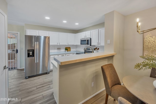 5808 E Brown Rd Unit 49, Mesa, AZ 85205 - kitchen with appliances with stainless steel finishes, light wood finished floors, white cabinetry, a peninsula, and light countertops