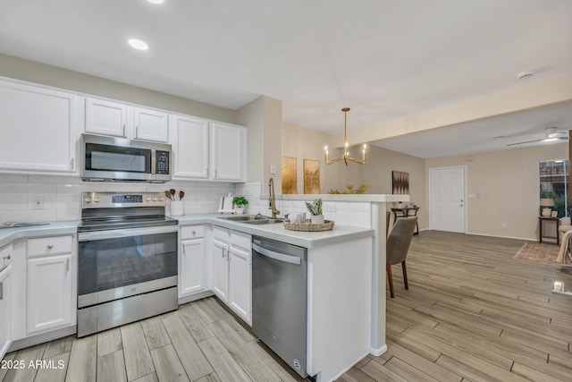 5808 E Brown Rd Unit 49, Mesa, AZ 85205 - kitchen with appliances with stainless steel finishes, a sink, a chandelier, a peninsula, and decorative backsplash