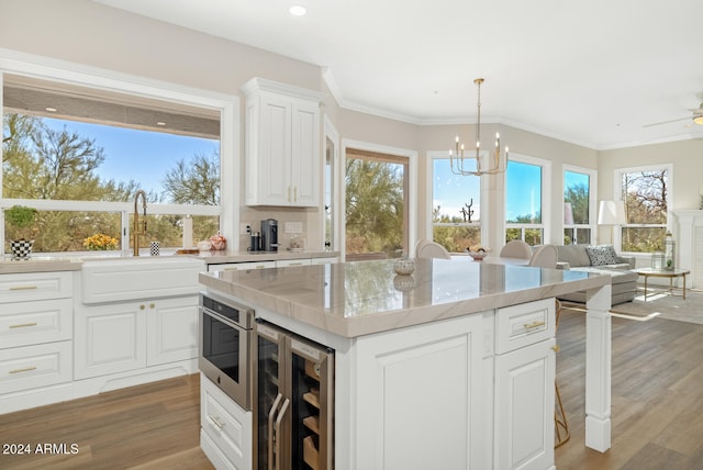 kitchen with a center island, white cabinetry, beverage cooler, and hardwood / wood-style floors