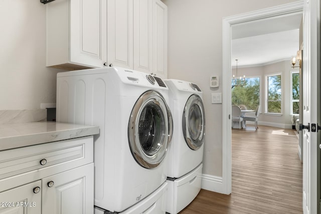 washroom featuring cabinets, a notable chandelier, independent washer and dryer, and light wood-type flooring