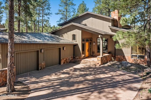 2096 William Palmer, Flagstaff, AZ 86005 - view of front of house with stone siding, a chimney, metal roof, an attached garage, and driveway