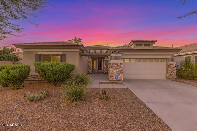 view of front of house with a garage, concrete driveway, stone siding, and stucco siding