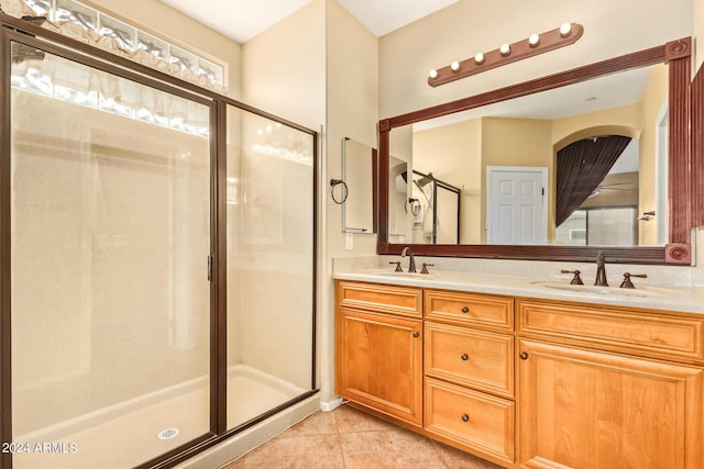 bathroom featuring double vanity, tile patterned flooring, a shower stall, and a sink