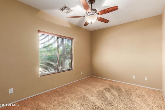 carpeted empty room featuring ceiling fan, visible vents, and baseboards