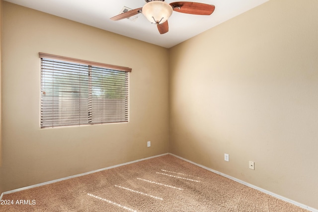 carpeted spare room featuring baseboards and a ceiling fan