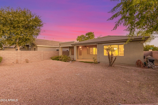 view of front facade featuring a patio, a fenced backyard, a tiled roof, and stucco siding