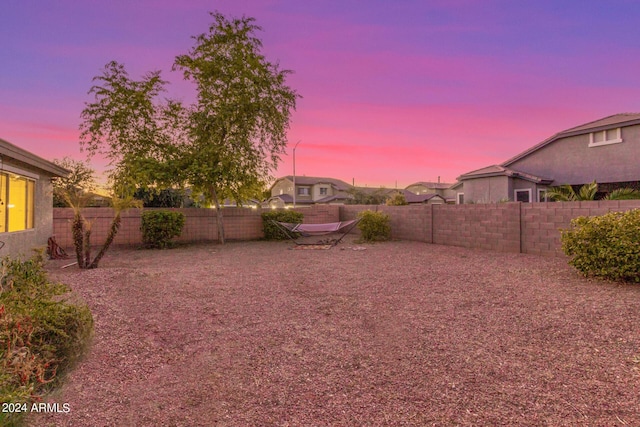 yard at dusk featuring a fenced backyard