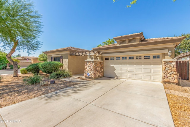 view of front facade with a garage, fence, stone siding, driveway, and stucco siding