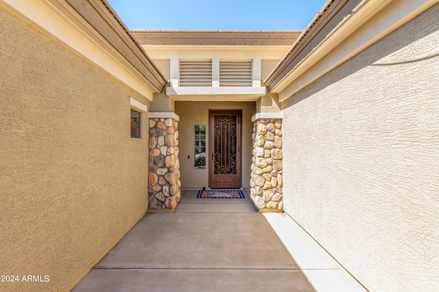 doorway to property with stone siding and stucco siding