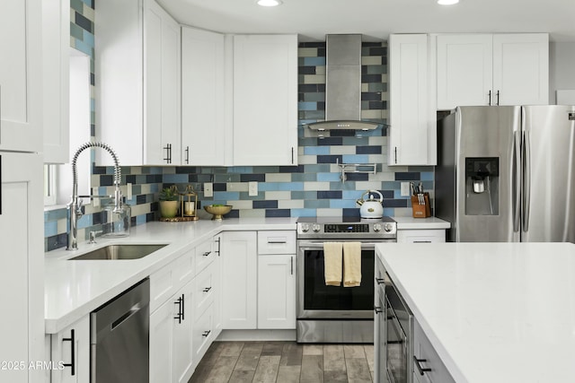 kitchen featuring wall chimney range hood, tasteful backsplash, stainless steel appliances, and a sink