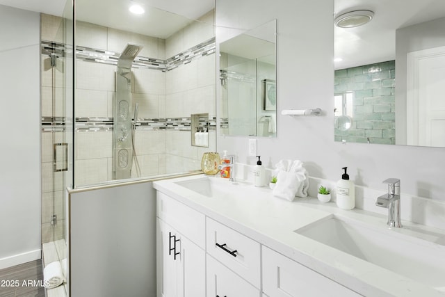 full bathroom featuring double vanity, a stall shower, and a sink