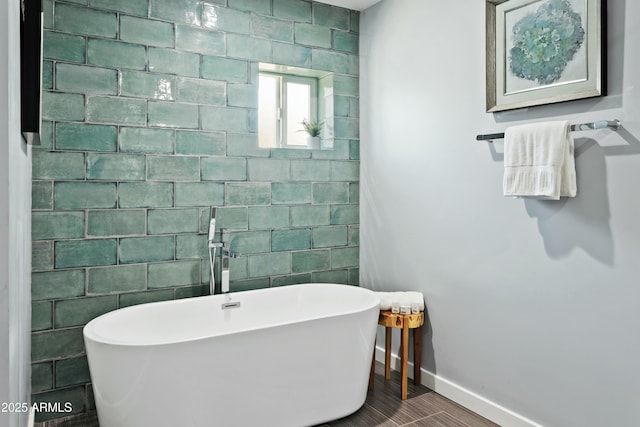 bathroom with a freestanding bath, baseboards, and wood finished floors