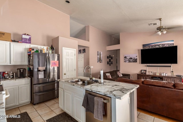 kitchen with sink, stainless steel appliances, light stone counters, an island with sink, and white cabinets