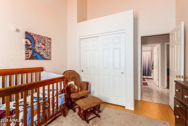 bedroom with a high ceiling, light hardwood / wood-style floors, and a closet