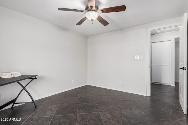 unfurnished room featuring ceiling fan and dark tile patterned flooring