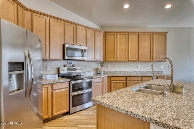 kitchen with light stone counters, stainless steel appliances, light hardwood / wood-style floors, and sink