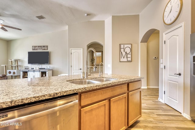 kitchen with sink, light hardwood / wood-style flooring, ceiling fan, vaulted ceiling, and stainless steel dishwasher