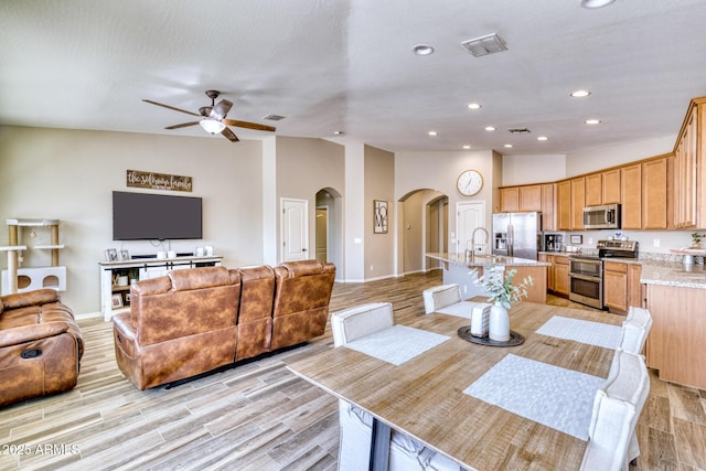 dining space featuring vaulted ceiling, sink, ceiling fan, and light wood-type flooring