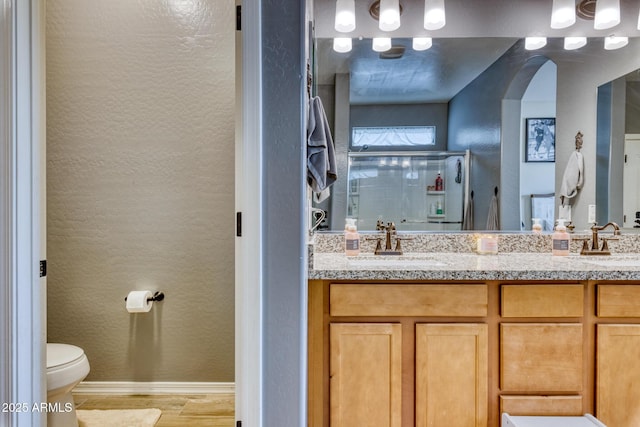 bathroom featuring vanity, hardwood / wood-style floors, a shower with door, and toilet